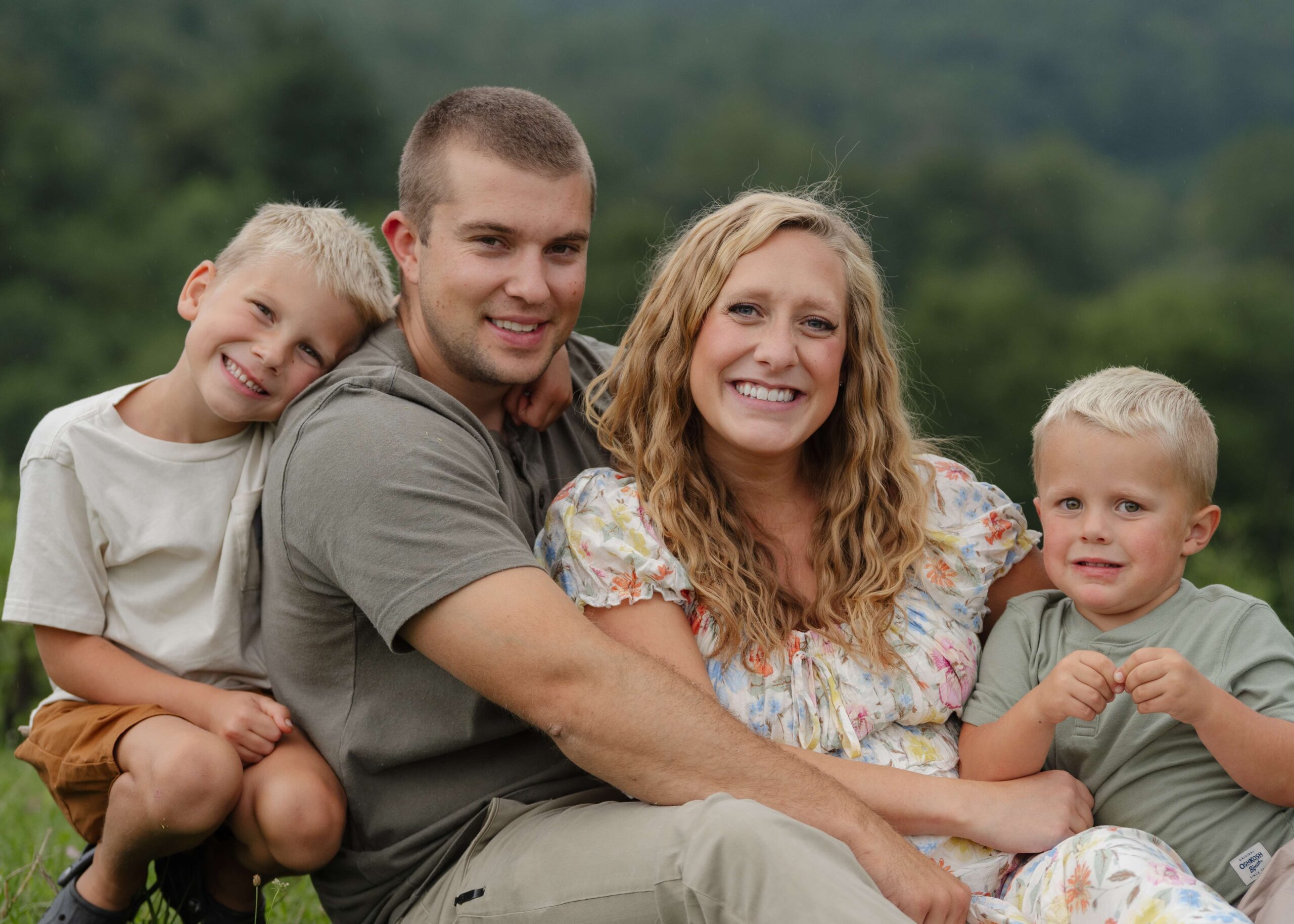 Boone, North Carolina family sits in an open field on their property to pose for a lifestyle family and maternity session.