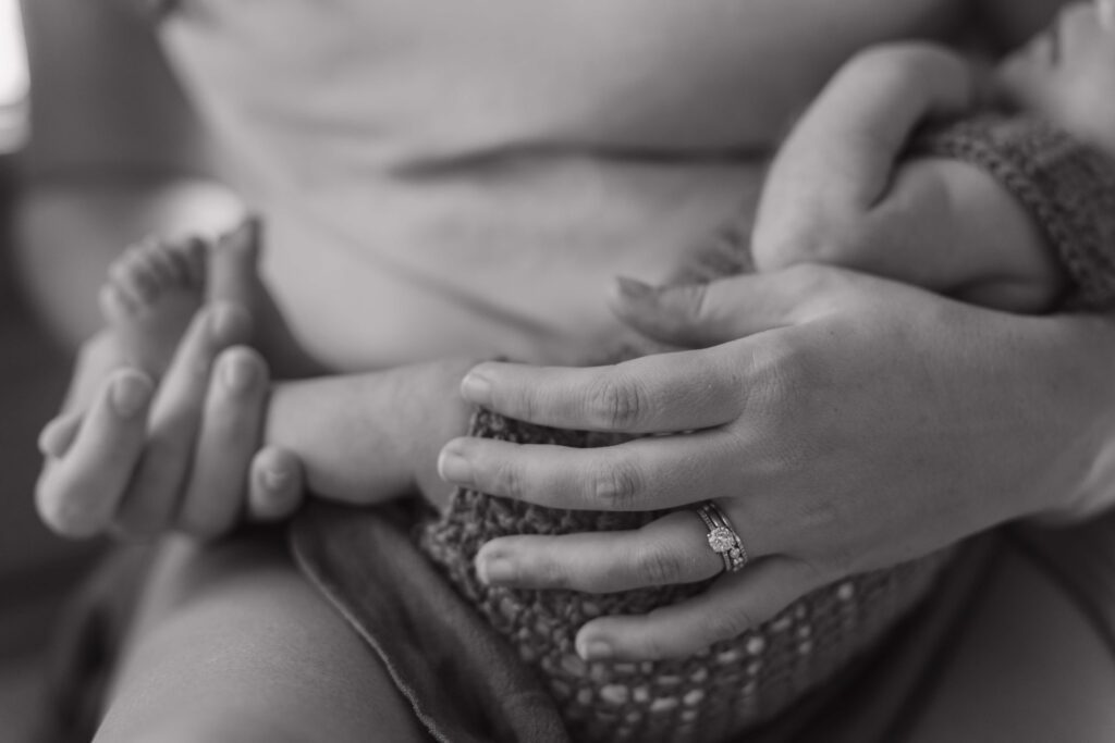 Detail photo of a mother holding her 3rd newborn son in between moments during their in-home lifestyle newborn photoshoot in Boone NC.
